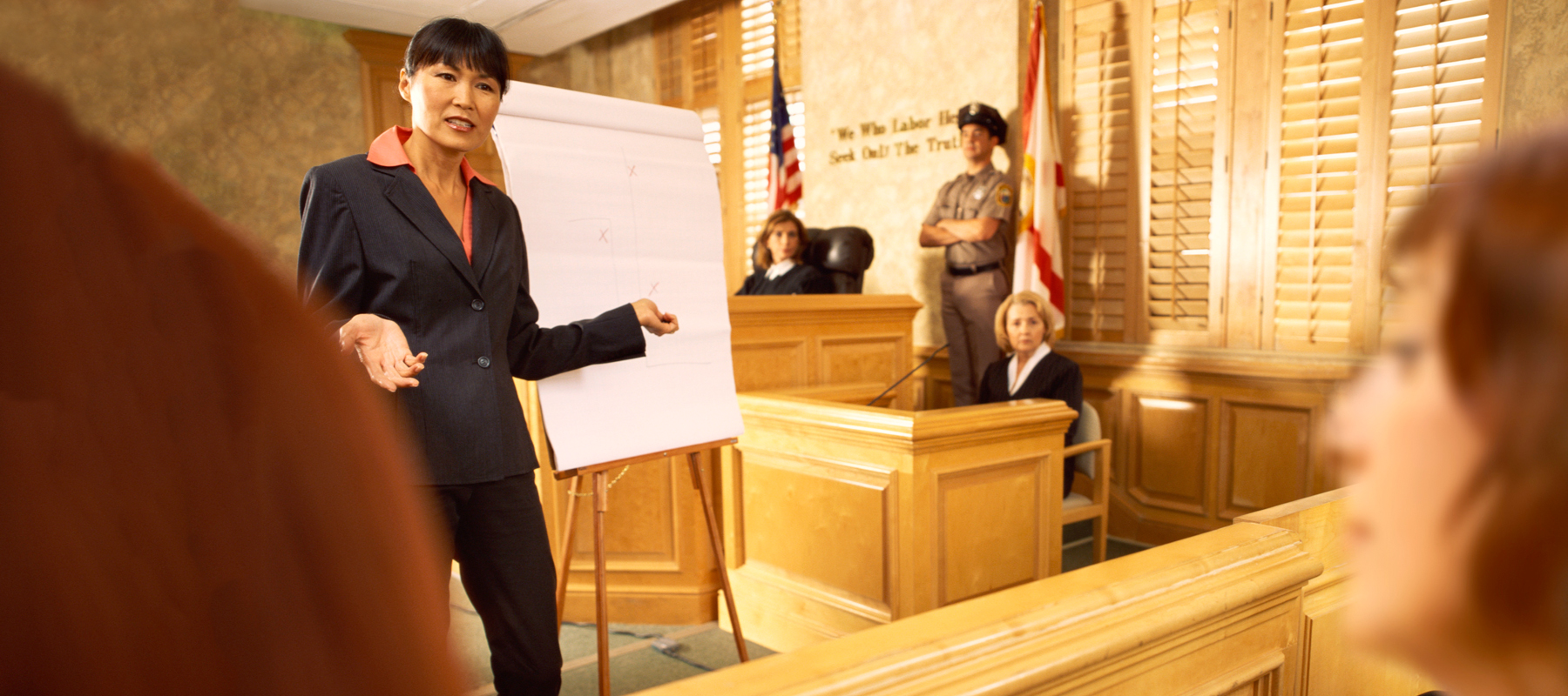 female in a suit talks to a jury in a court room