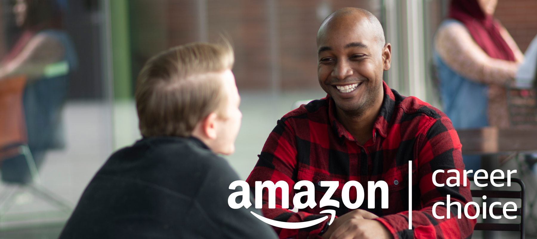 black male sitting in a red and black checked shirt smiling