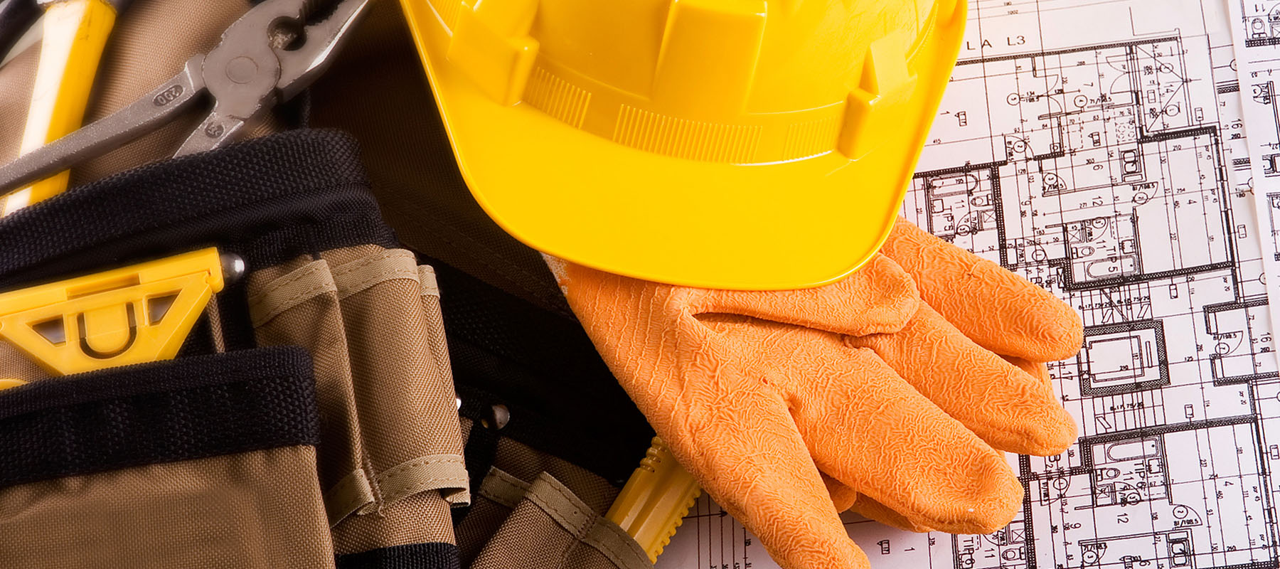 yellow hard hat, work gloves and tool belt next to building plans