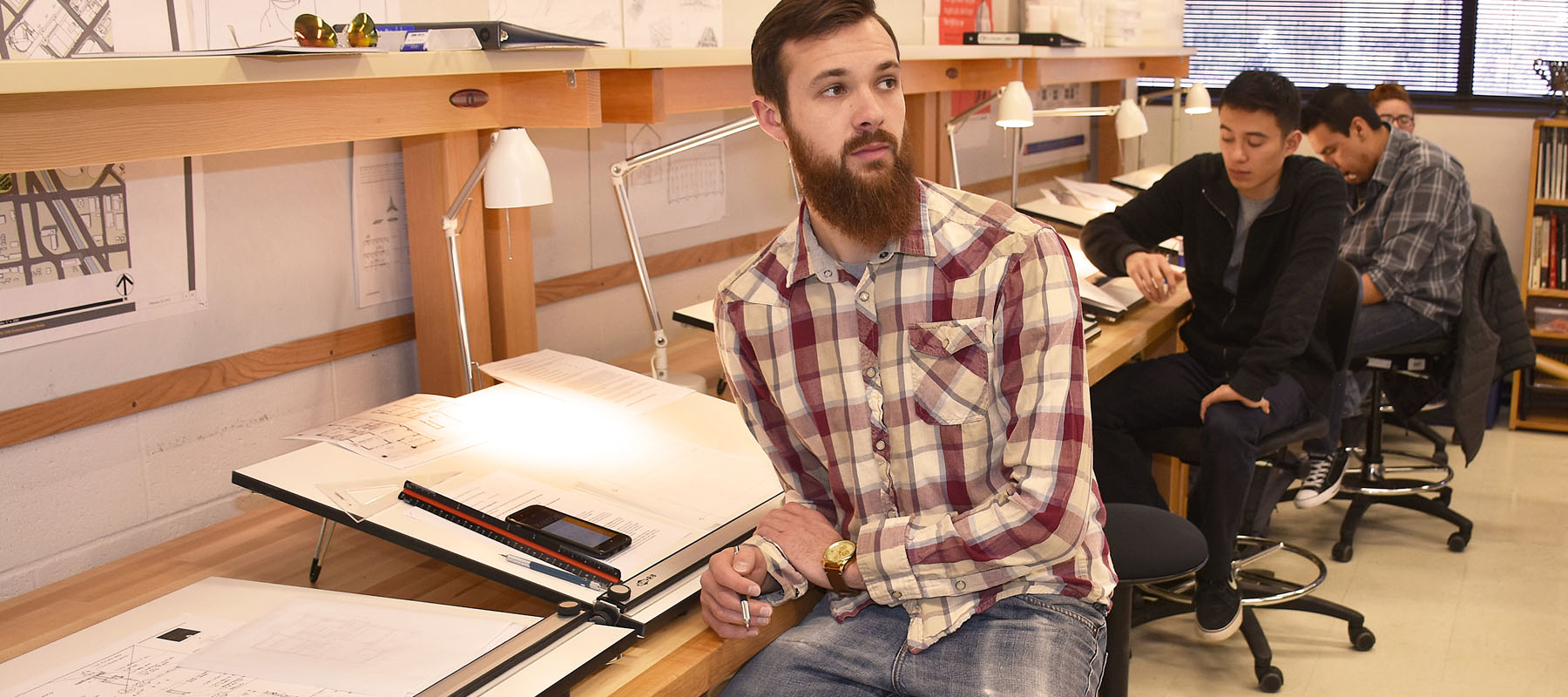 male student sits at a drafting table during class