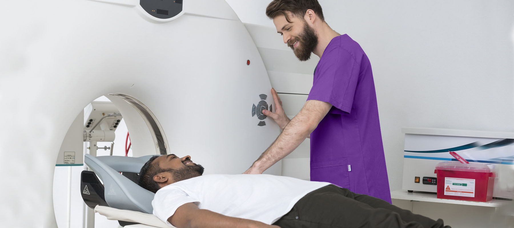 man wearing purple scrubs prepares a patient for a CT