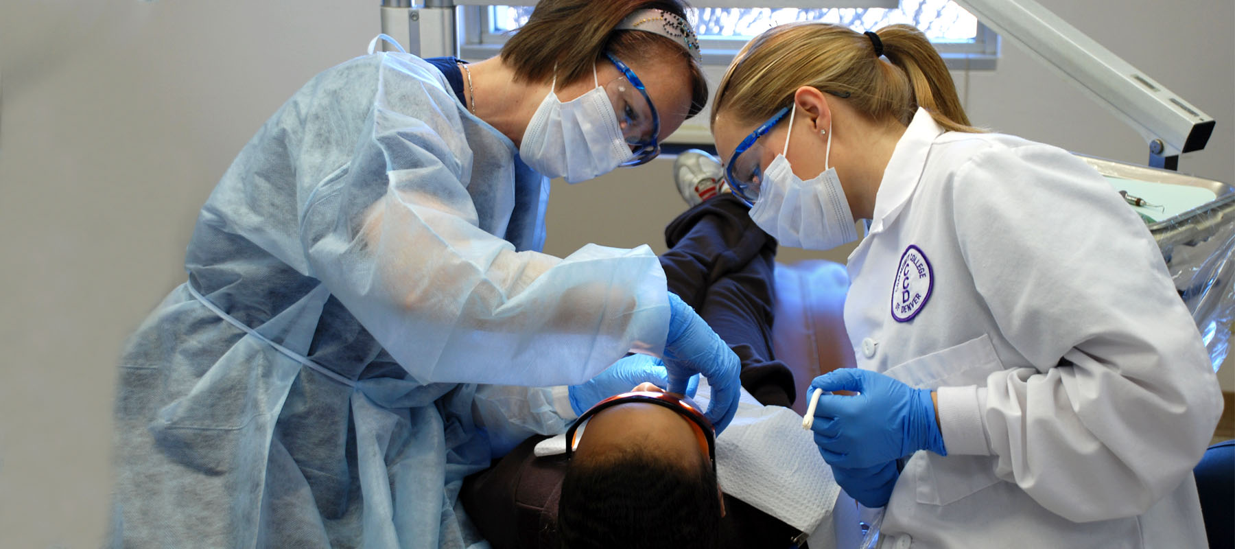 dental hygenists in protective gear with a patient