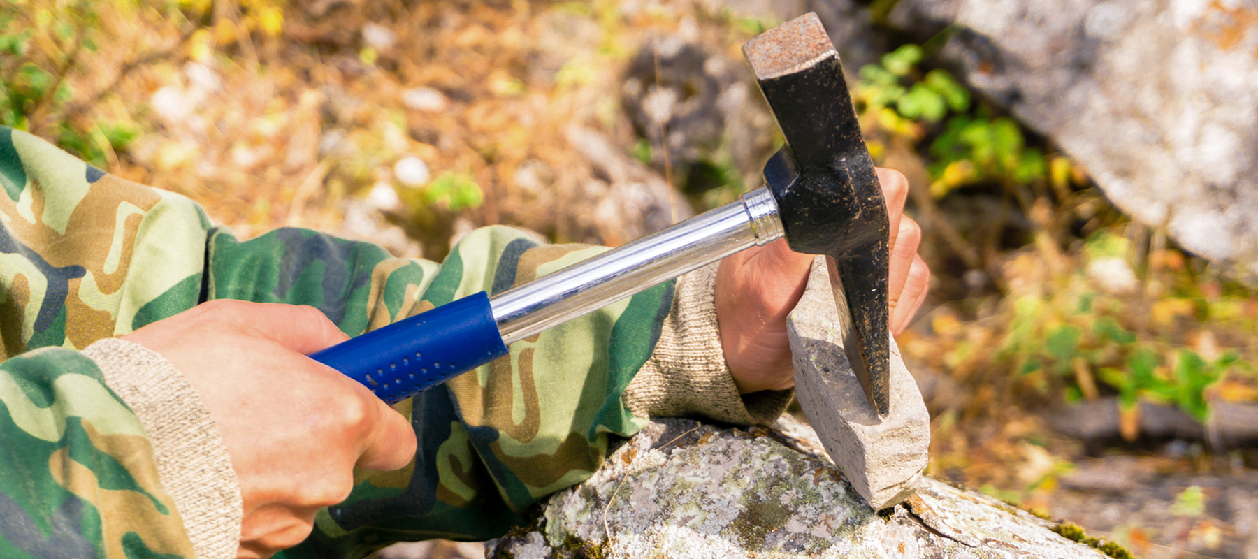 person using a hammer to break open a rock