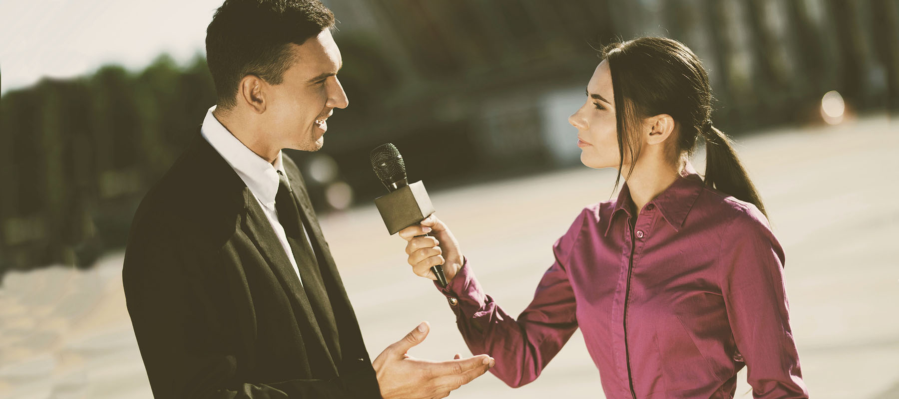 woman holds a microphone interviewing a man