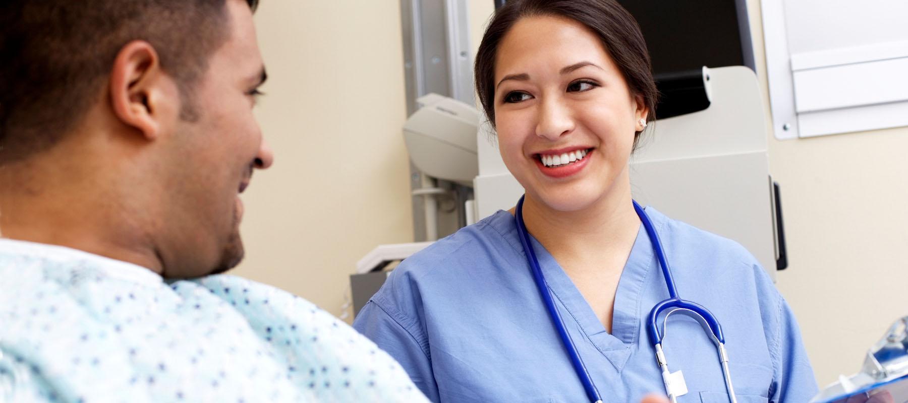 female in blue scrubs speaking with a male patient