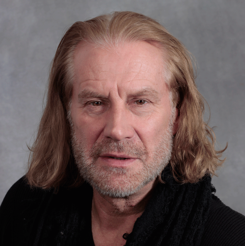 Man with longish red hair, closed cropped beard and black shirt