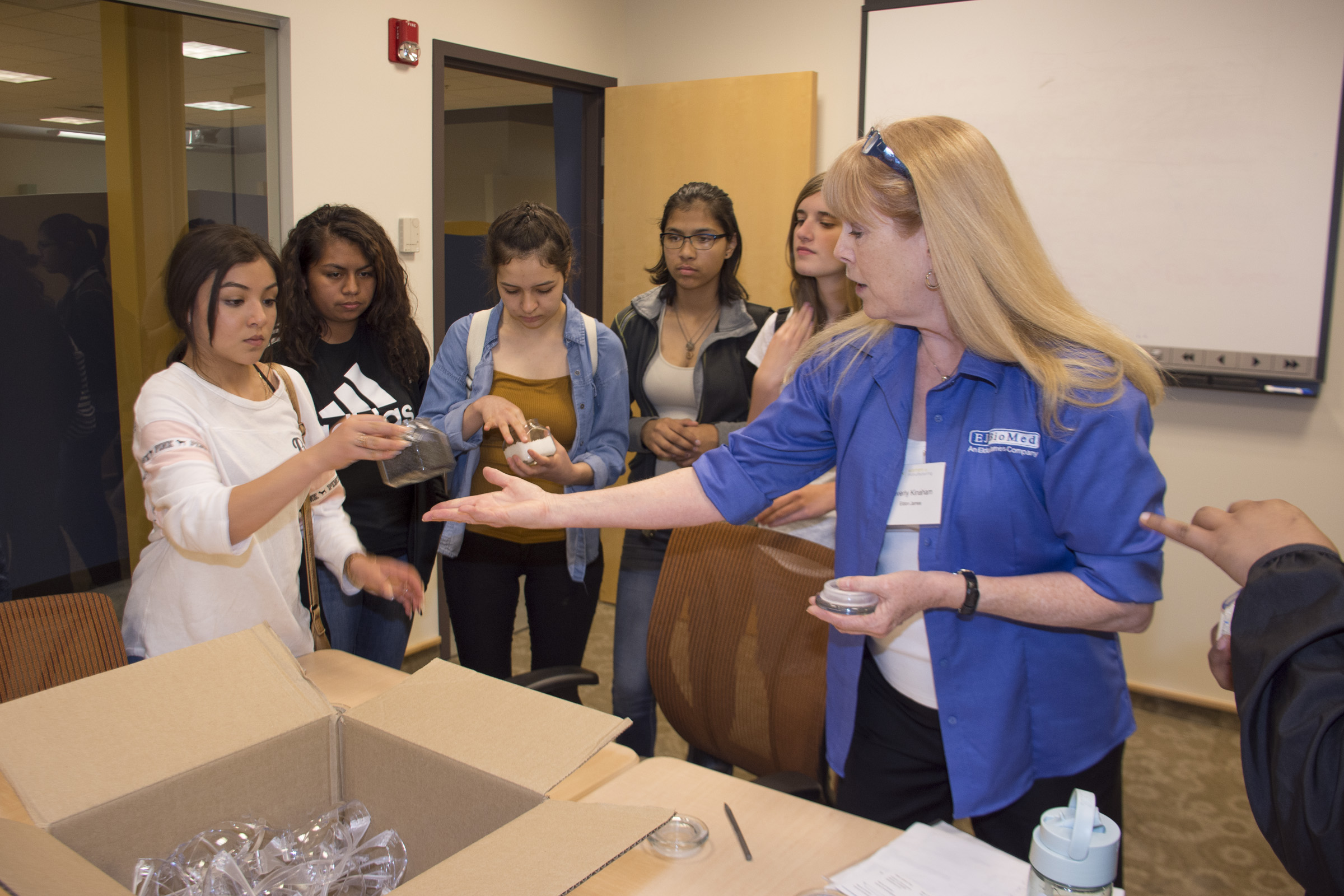 woman in blue shirt shows young females machining products