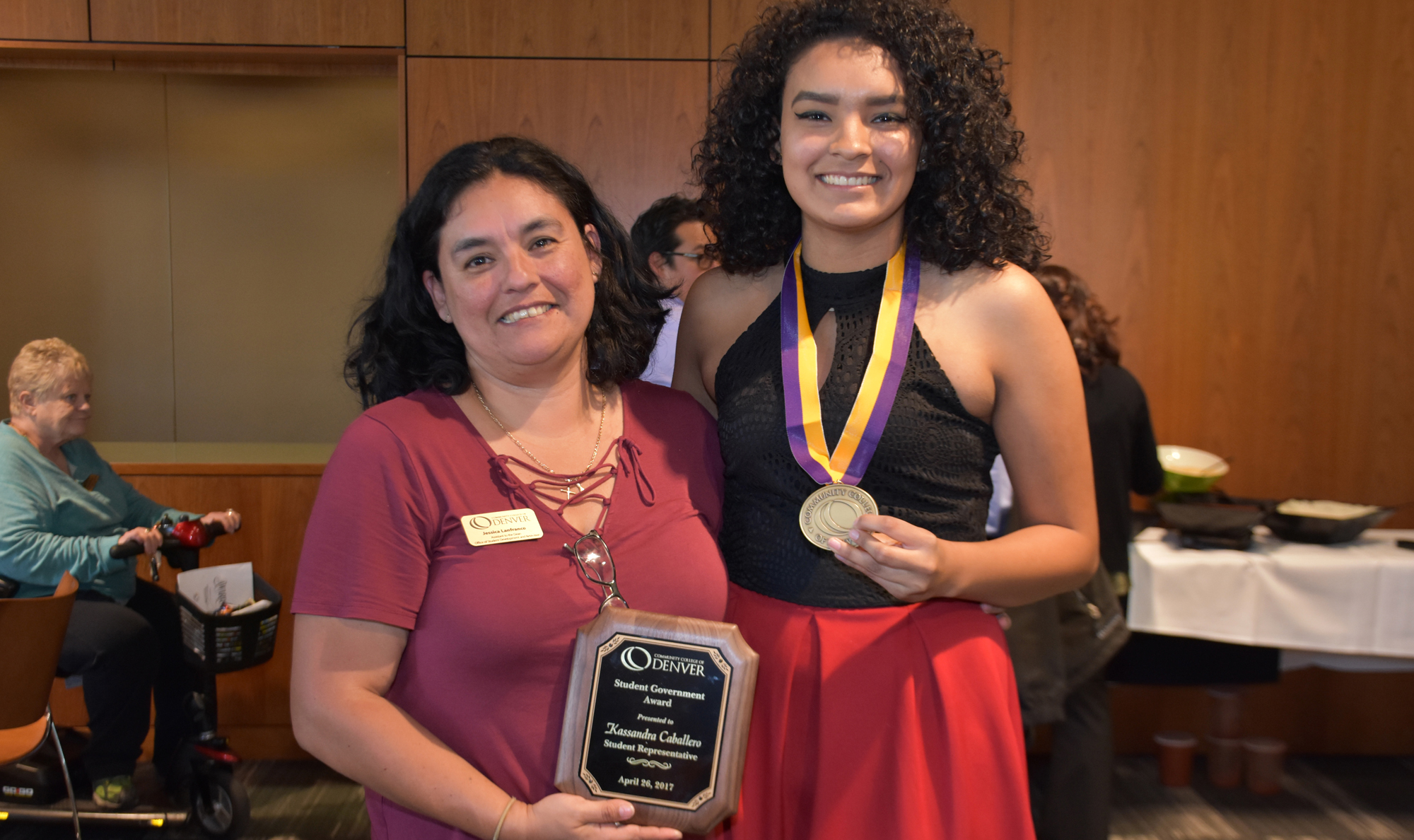 student wearing medal standing next to woman holding award