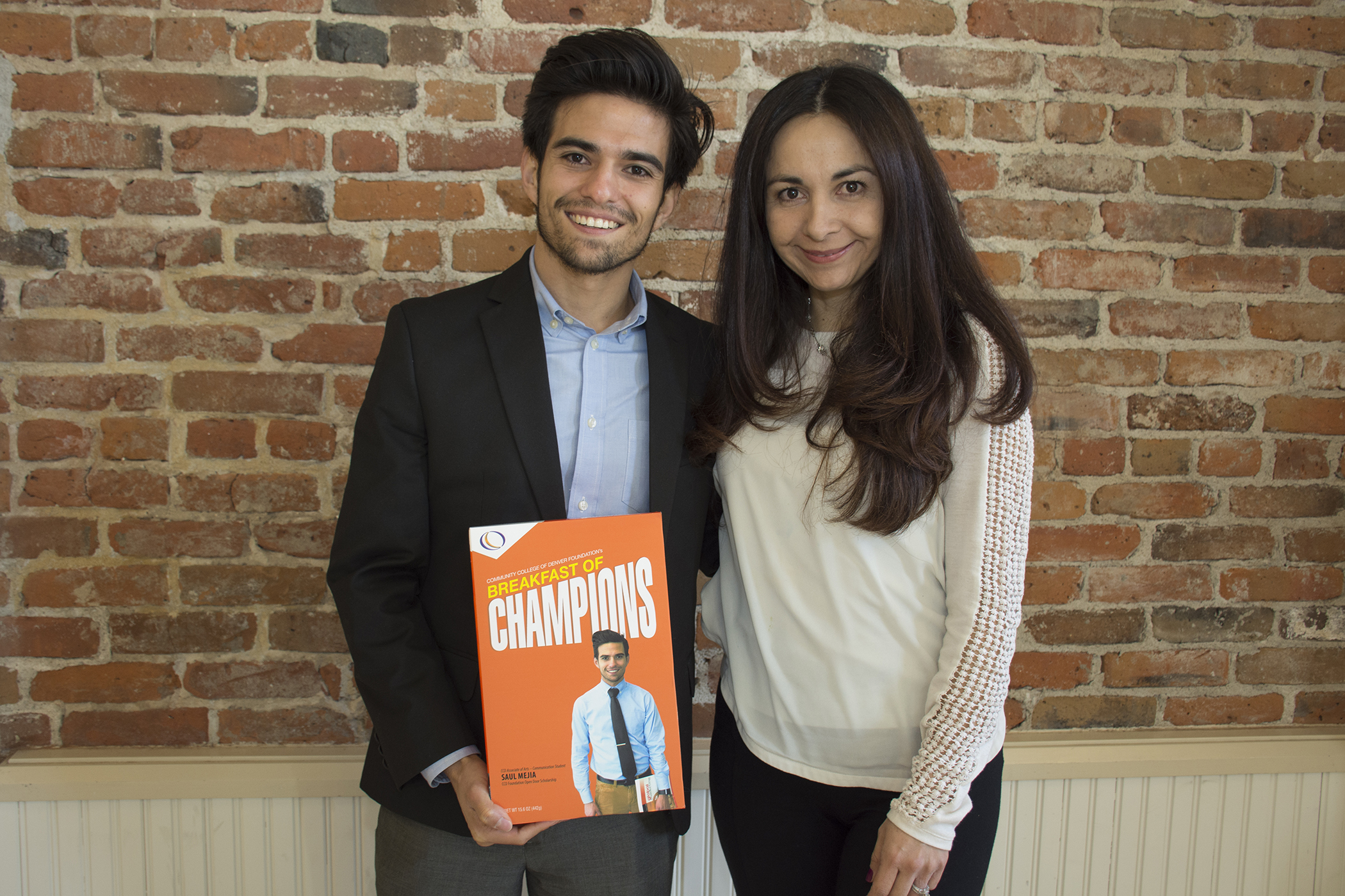 young Hispanic male standing with a Hispanic women smiling and holding a box of cereal