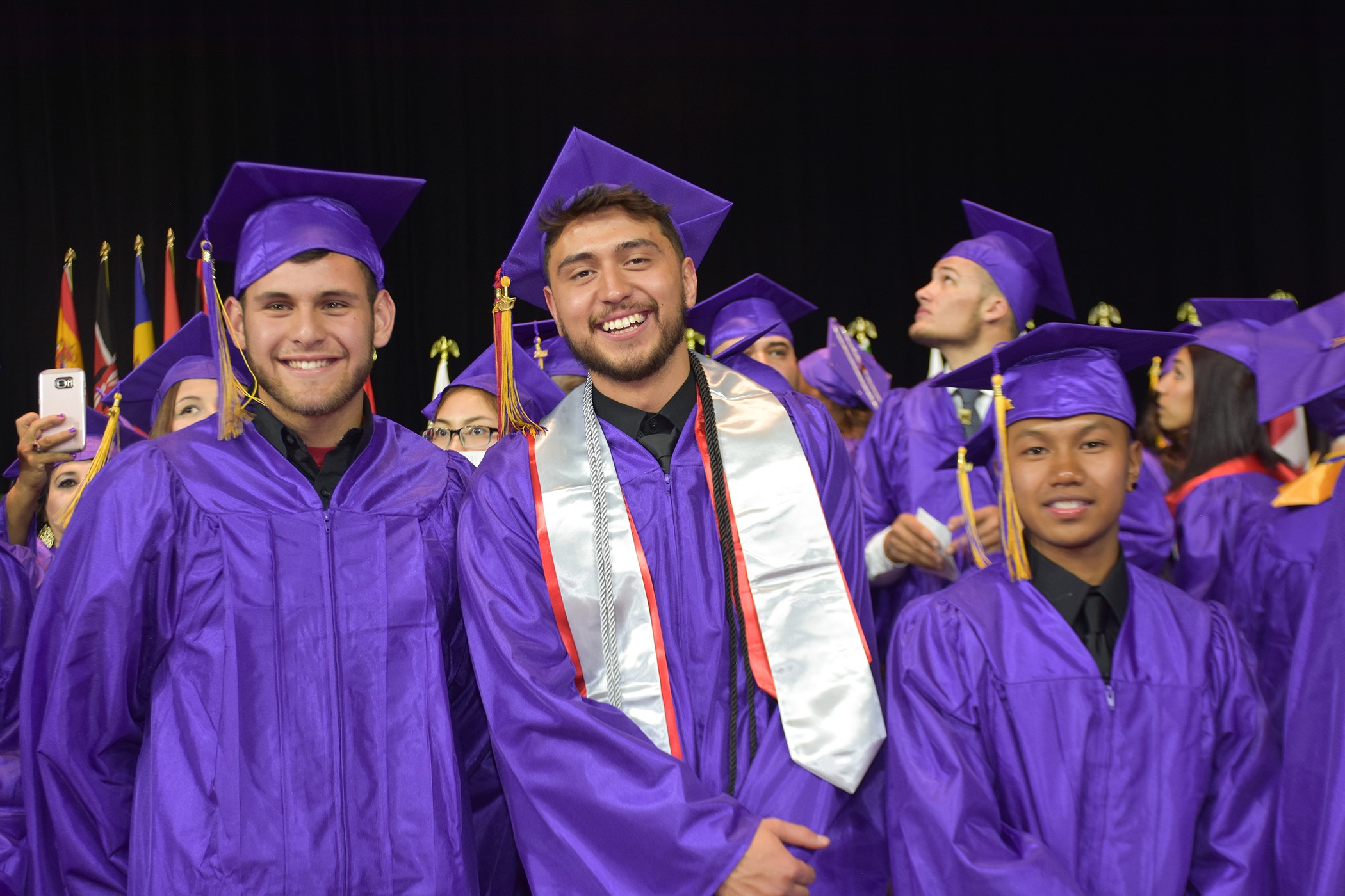 Congrats to All Our Grads! three male grads at commencement in cap and gown