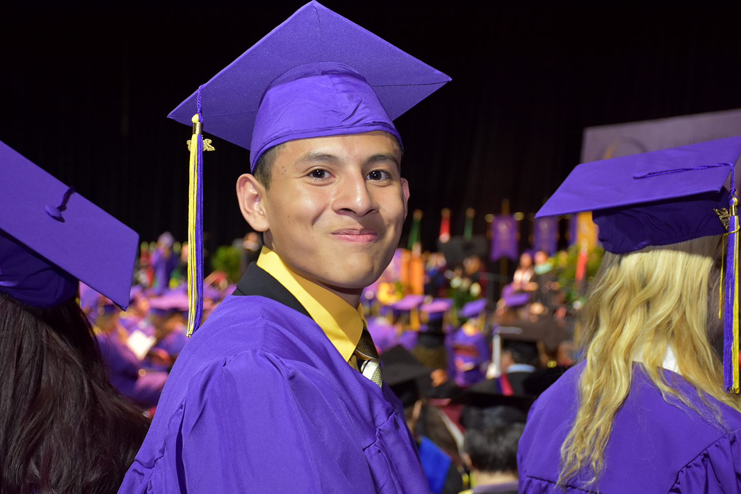 young man in cap and gown smiles
