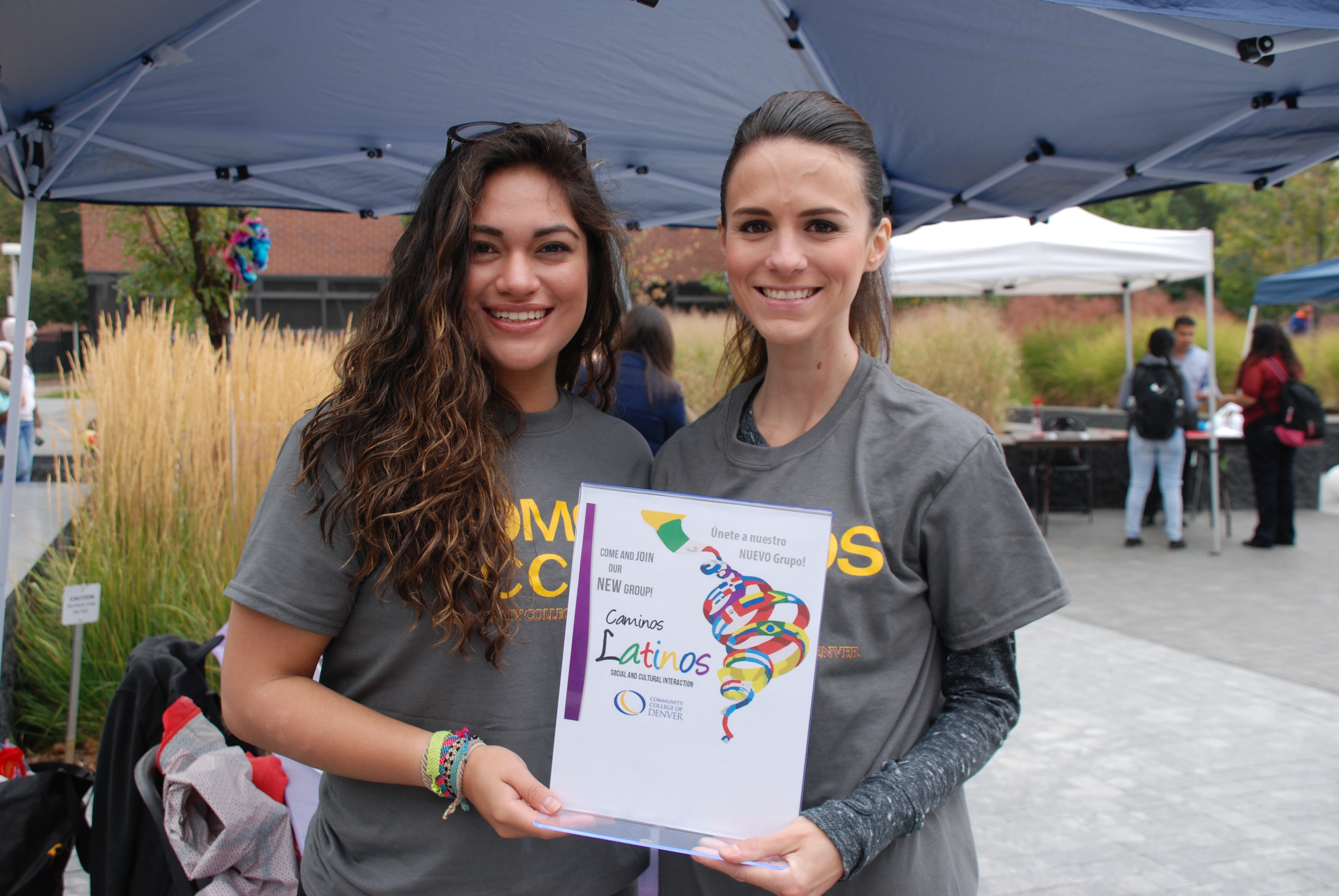 two females in matching SOMOS tshirts holding a certificate