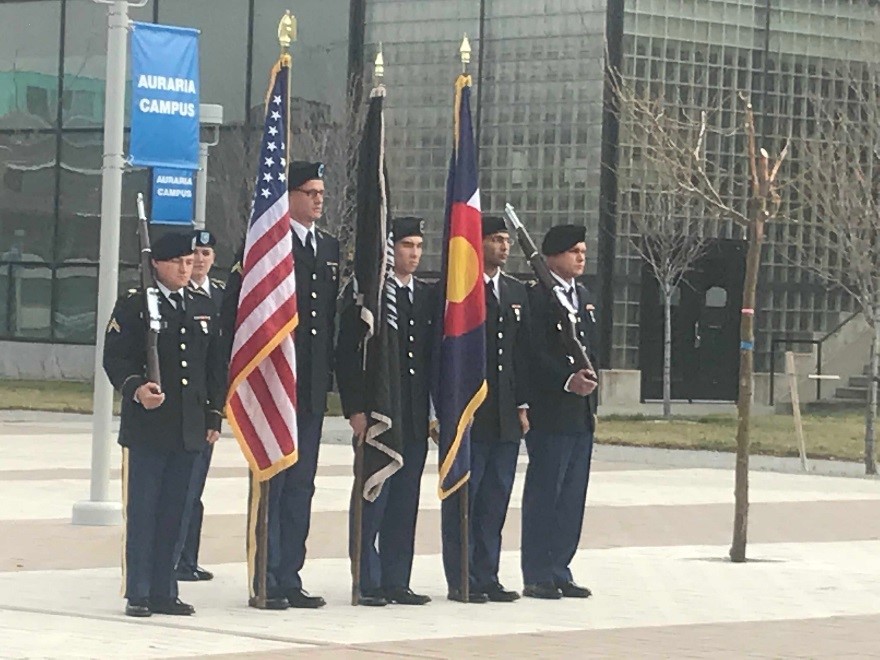 5 miliary men standing at attention in a row holding flags