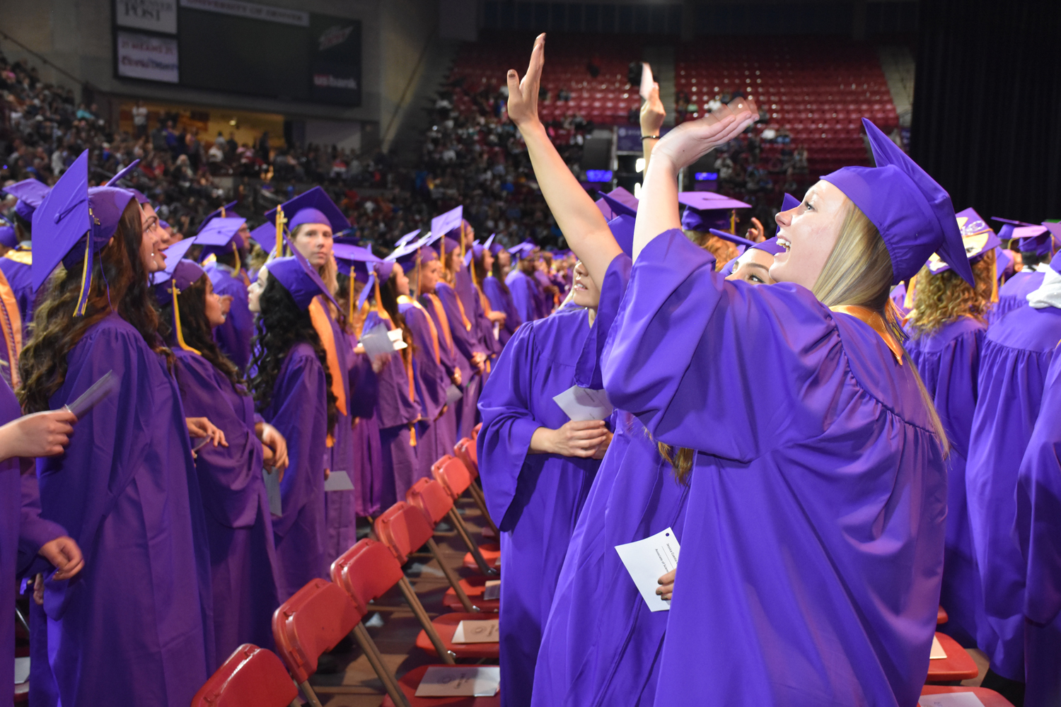 people in purple caps and gowns waving
