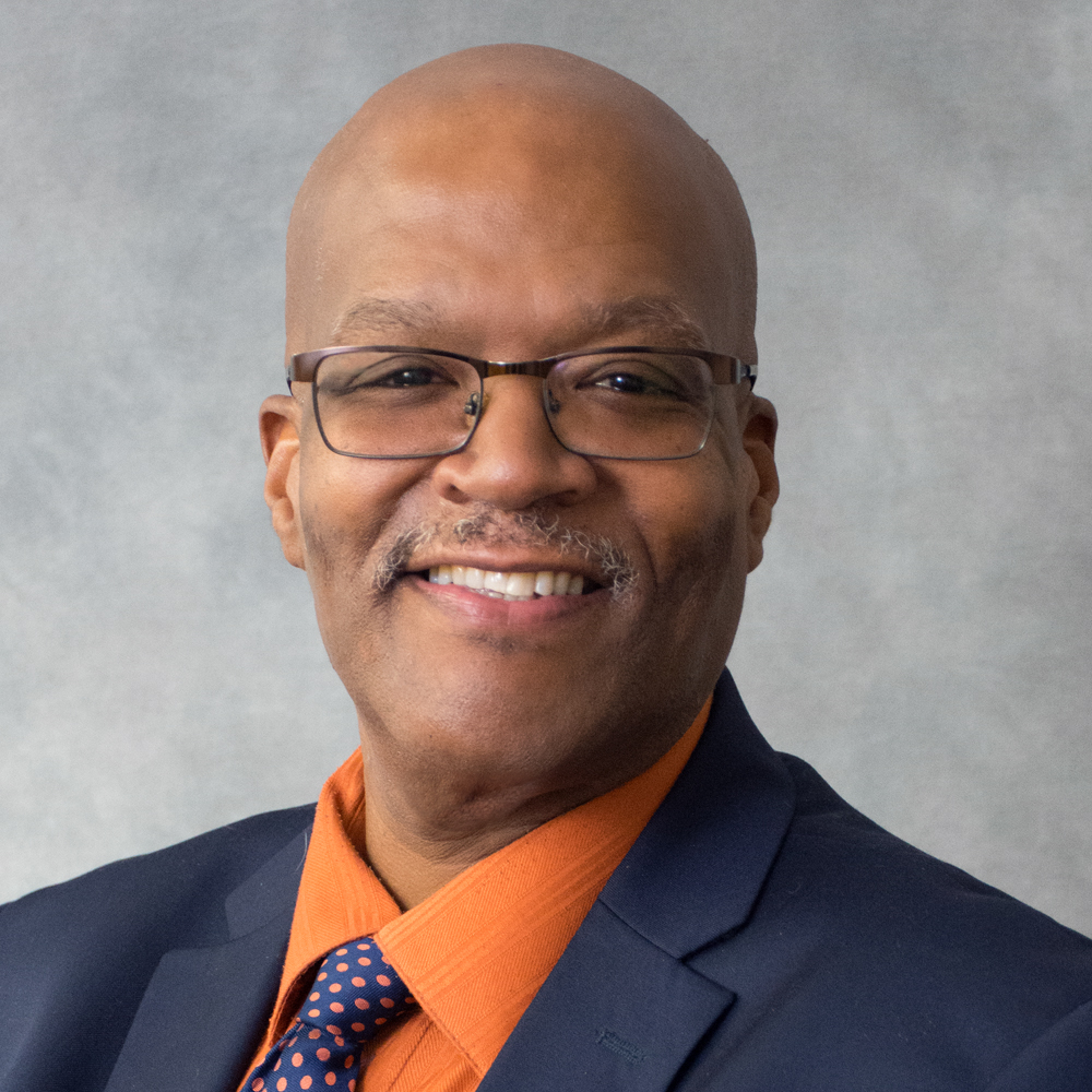 man with glasses in a blue shirt and orange shirt