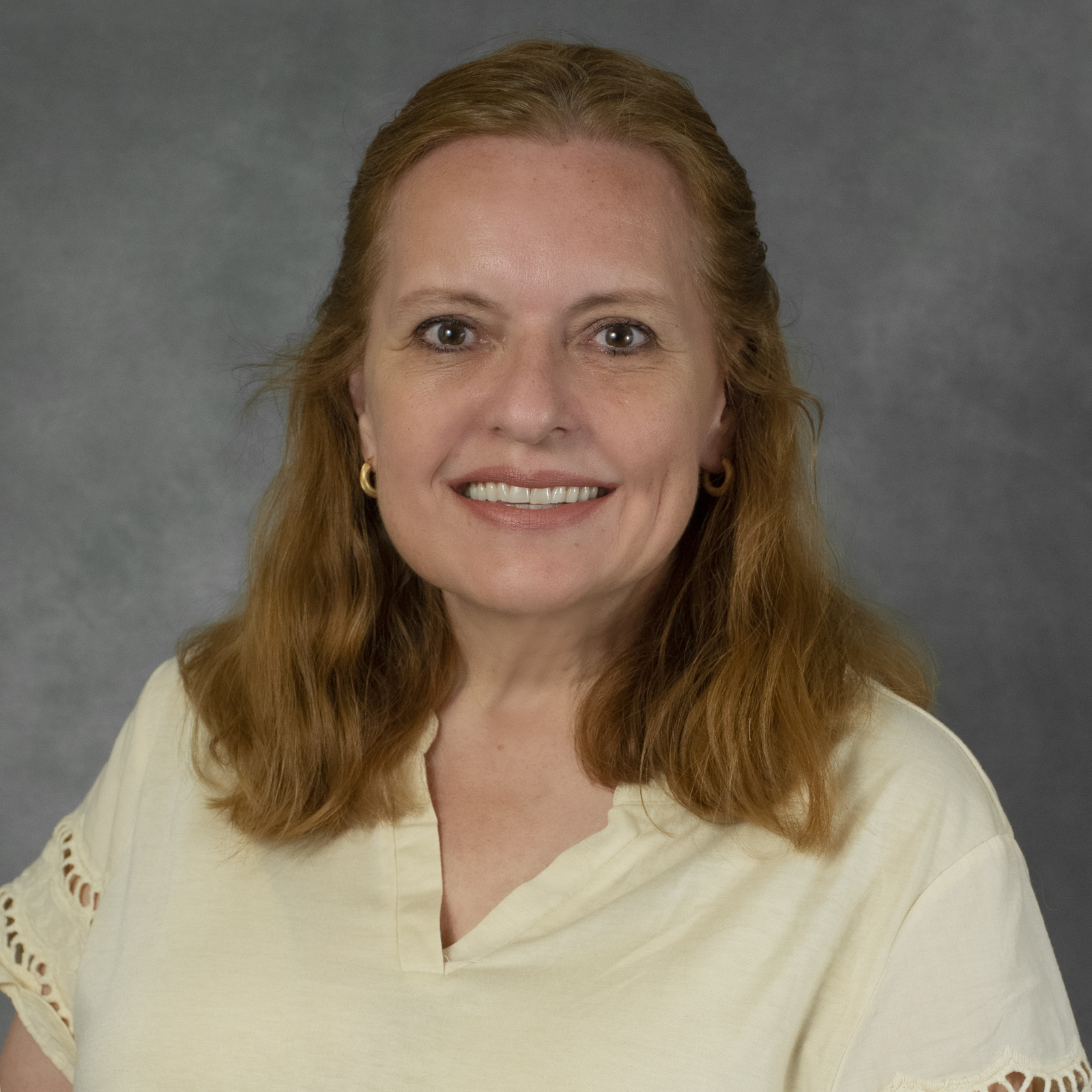 smiling woman with shoulder length red hair wearing a pale yellow blouse