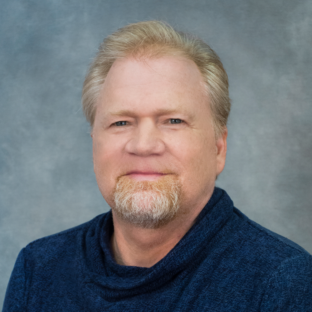 Person with a goatee wearing a dark blue shirt