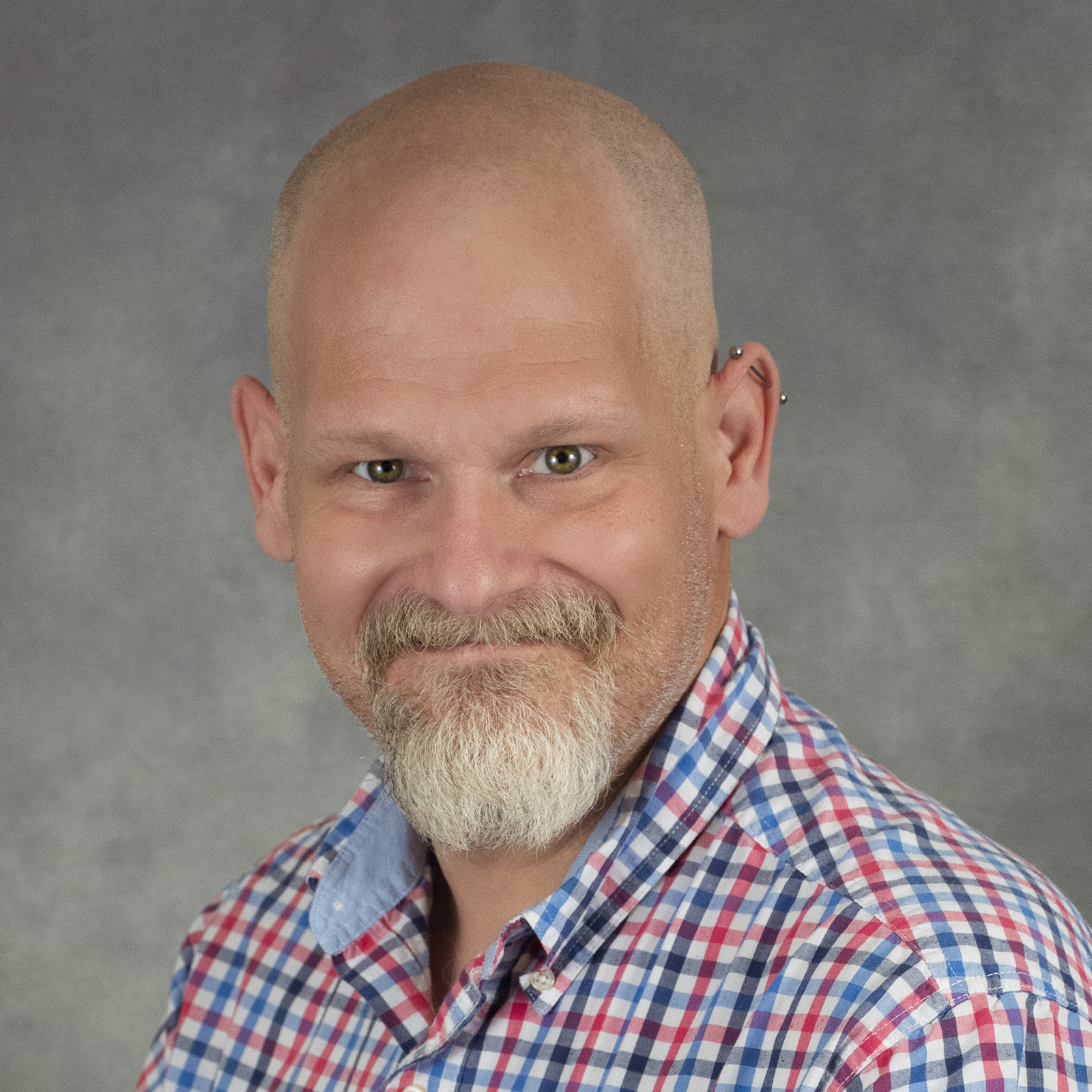 Smiling person with a goatee in a plaid shirt