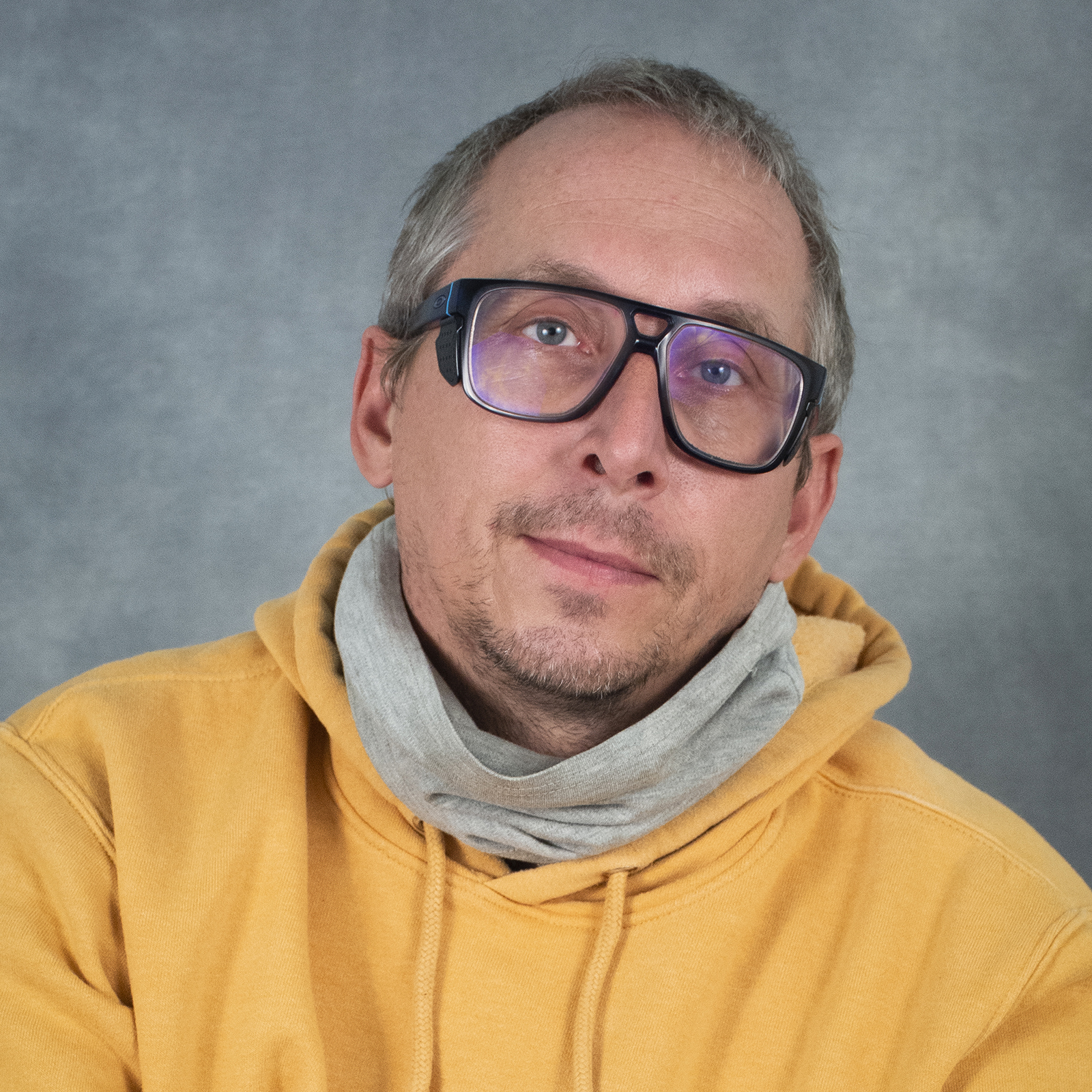Man wearing a yellow hoodie and glasses