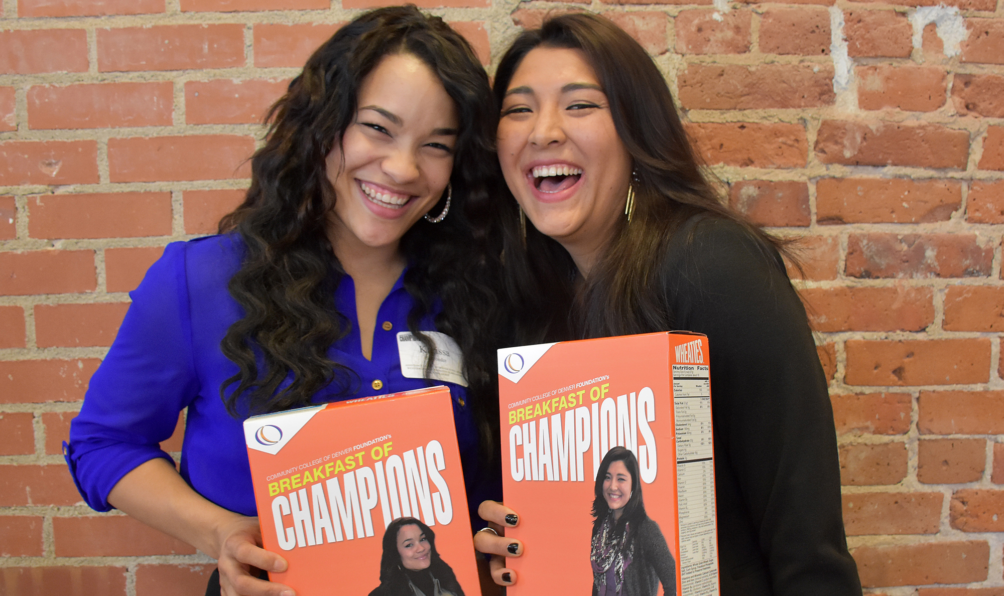 Two scholarship recipients at the Breakfast of Champions celebration two females holding cereal box of Breakfast of Champions