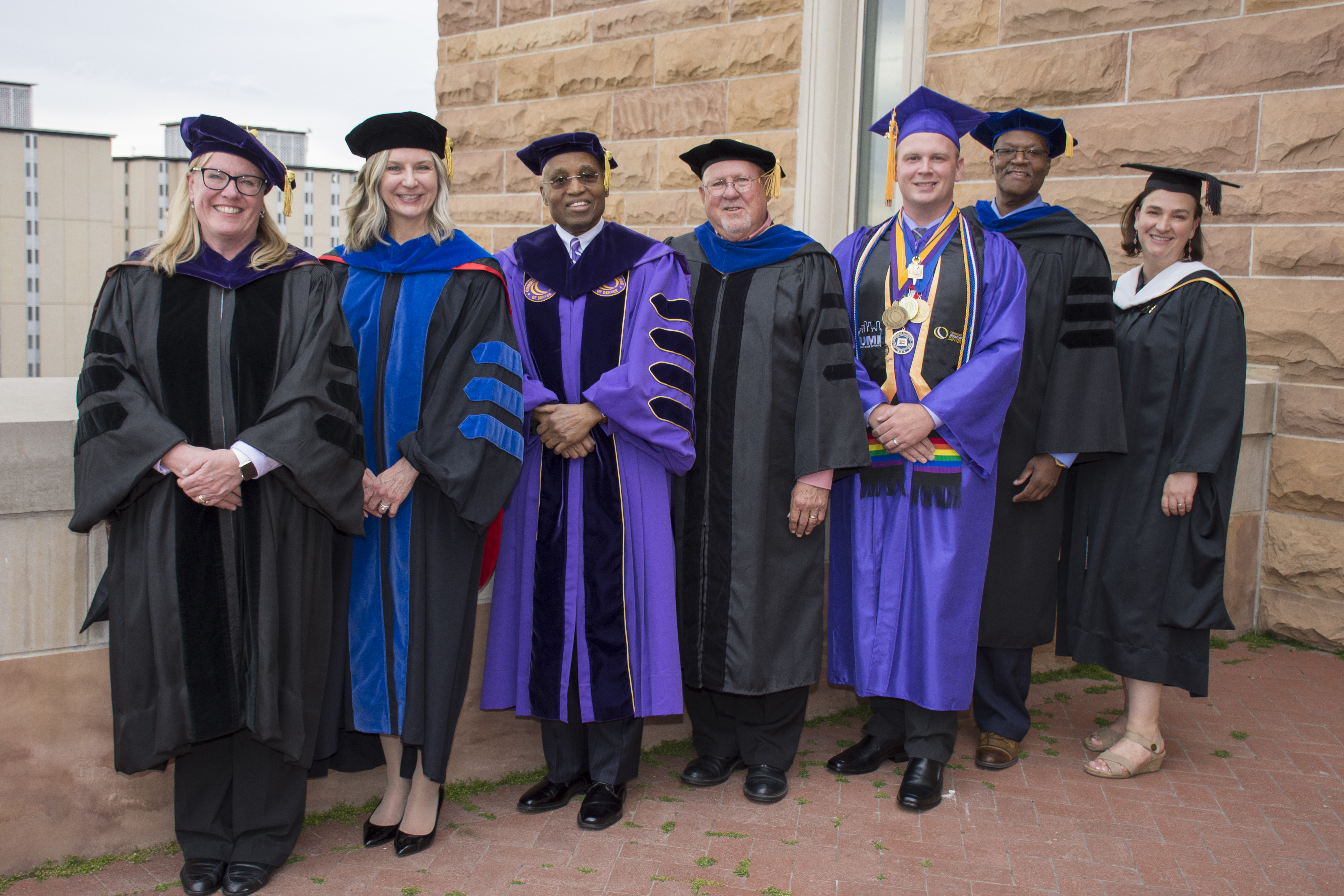 CCD's Leadership Team with Commencement Guest Speakers row of distinguished faculty and staff wearing caps and gowns