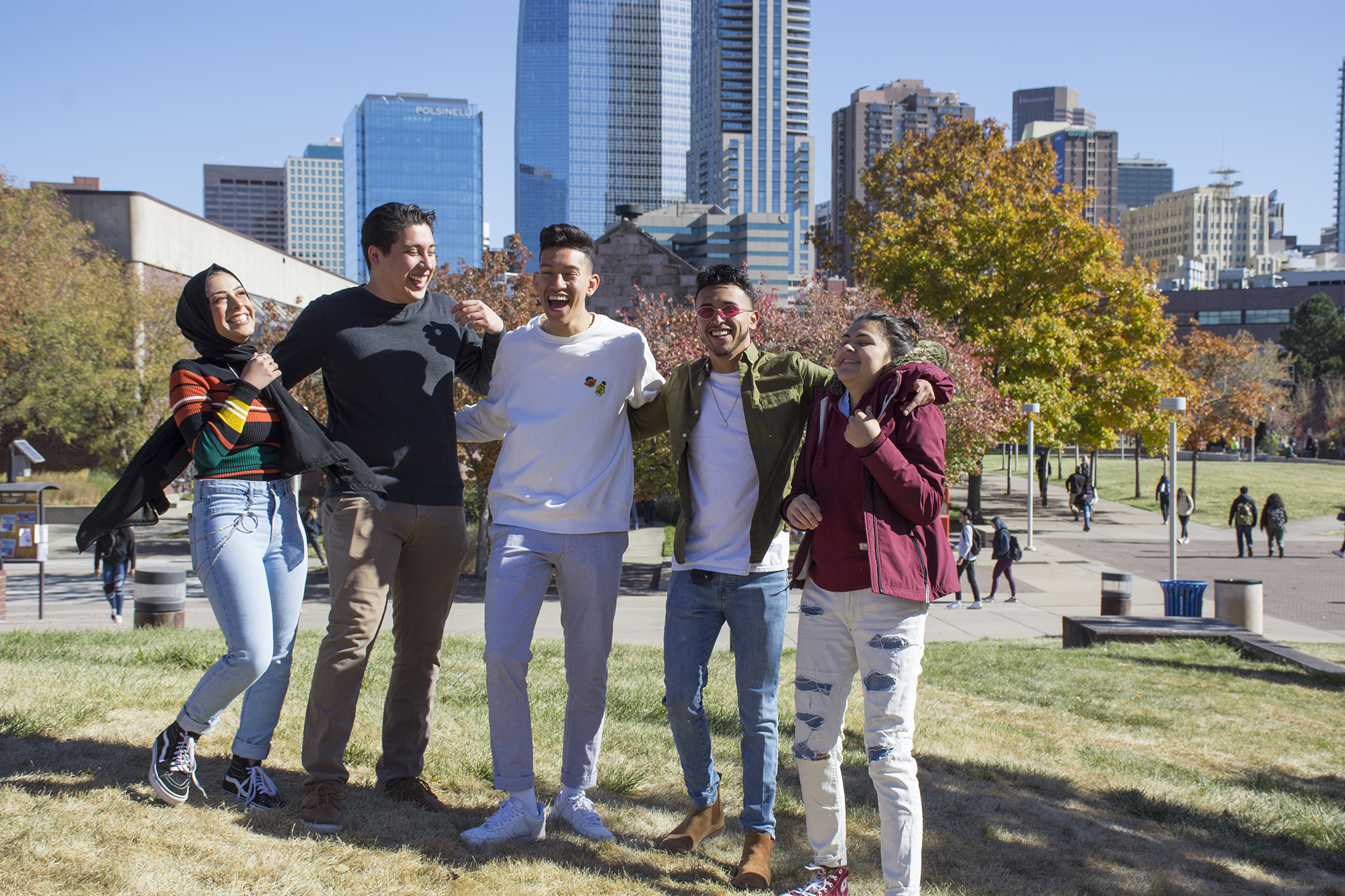 group of 5 students laughing on campus