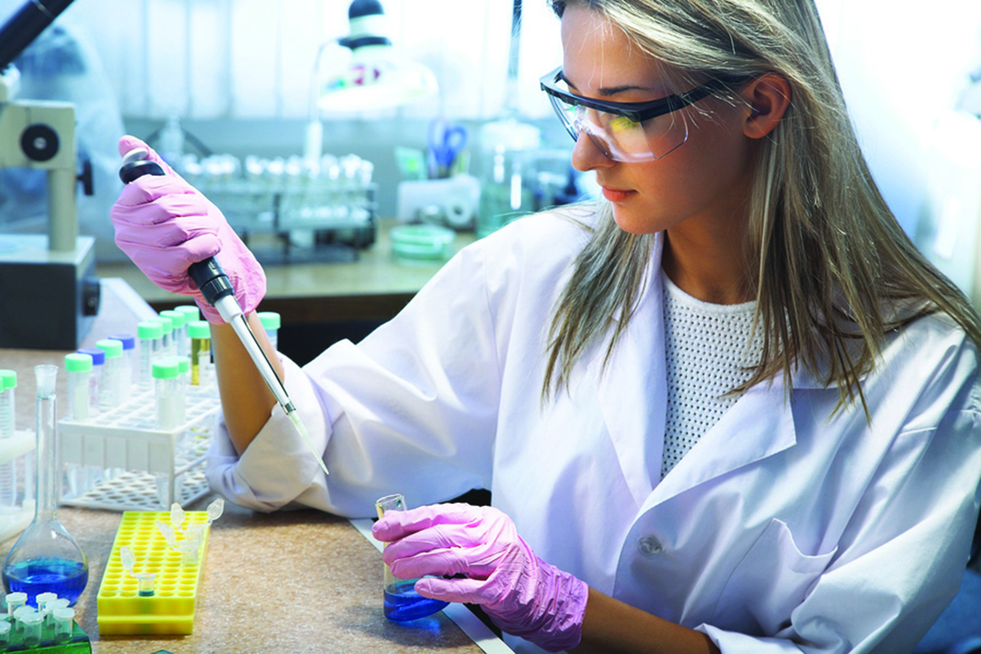 image of female student working in a lab setting with beakers and test tubes