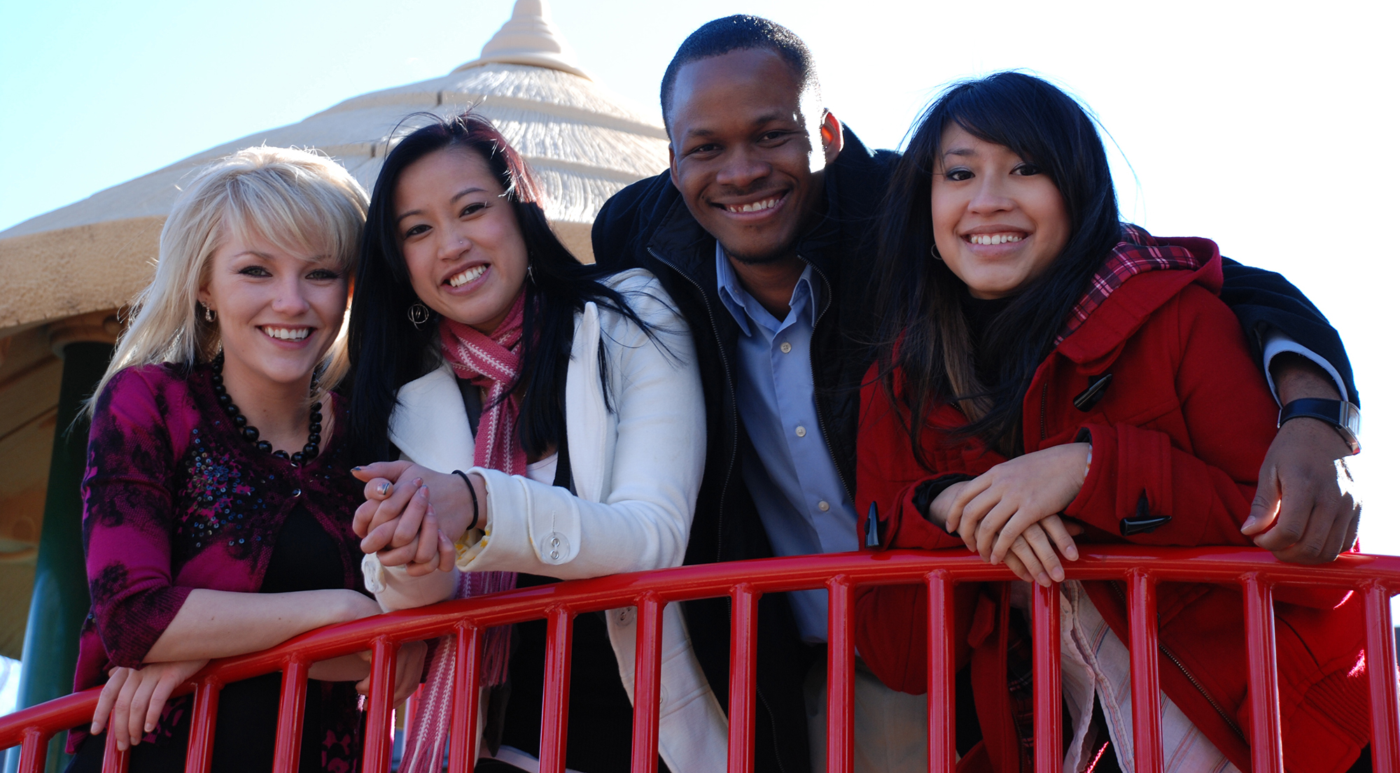 Four CCD students leaning on a red metal railing