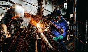 man in a machining helmet working with sparks