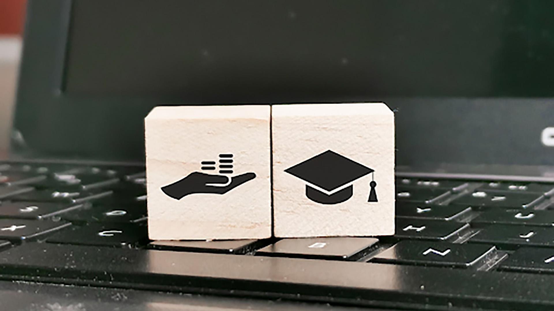 Stock image of block with hand and graduation cap on a laptop