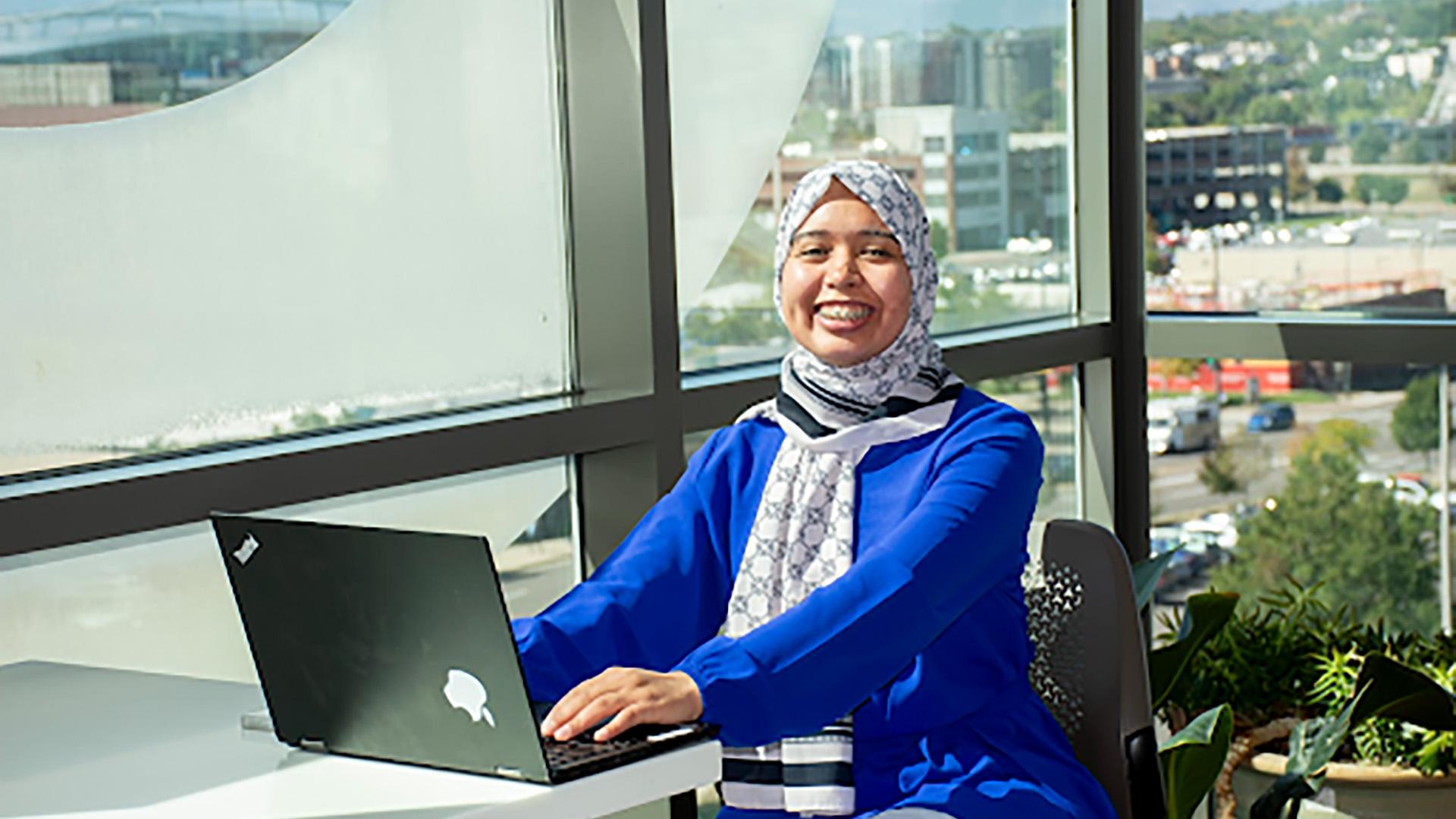 Students sitting at a tables on their laptops and iPads