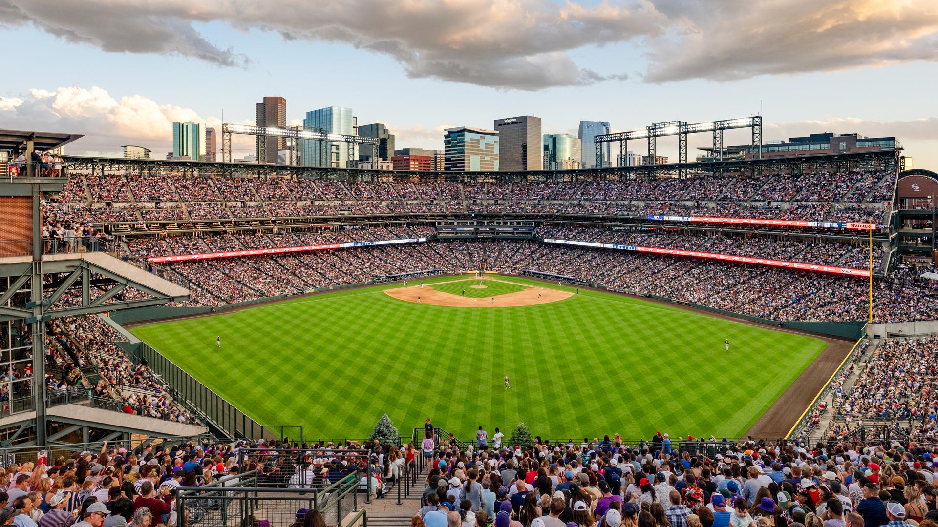 Image of Coors field on a summer day with clouds, fans, and a baseball field