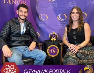 Man with facial hair in black jacket sitting next to a woman with brown hair wearing a patterned dress. CITYHAWK PODTALK.