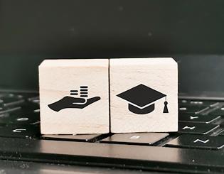 Stock image of block with hand and graduation cap on a laptop