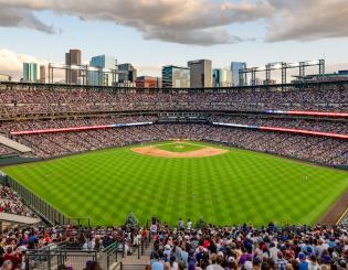 Image of Coors field on a summer day with clouds, fans, and a baseball field