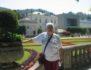 woman standing in front of gardens and large house