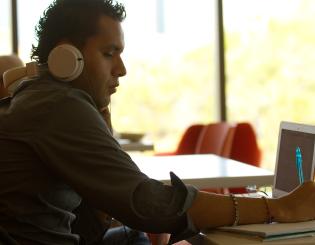 student with headphones at a laptop studying
