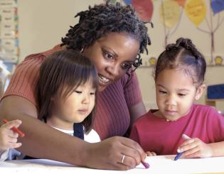 image of female teacher coloring with two pre-school girls