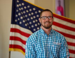 Colin seated in front of American flag