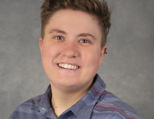 white woman in a blue shirt with short hair smiling
