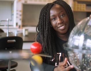 Female student looking at a solar system 3-d model