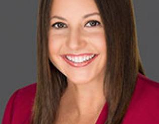 Hispanic woman wearing blue shirt and gray blazer
