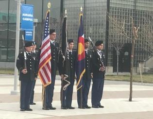 5 miliary men standing at attention in a row holding flags