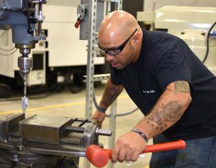 man in protective glasses learns to operate a machine