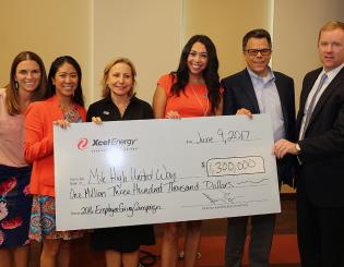 six people holding a large donation check from Xcel Energy