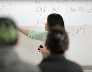 Math teacher at the white board pointing to math equations 