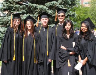 group of male and female graduates in black caps and gowns smiling