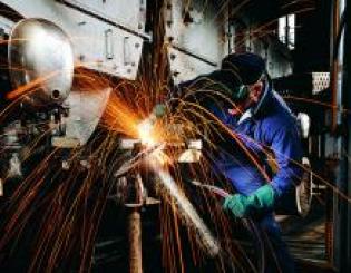 man in a machining helmet working with sparks