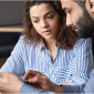 image of two people meeting and reading a paper. The women is in a striped shirt, while the bearded man is in a gray shirt 