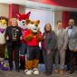 a group of seven people wearing business attire posing with three mascots; Swoop, Foxy, and Copper for the photo